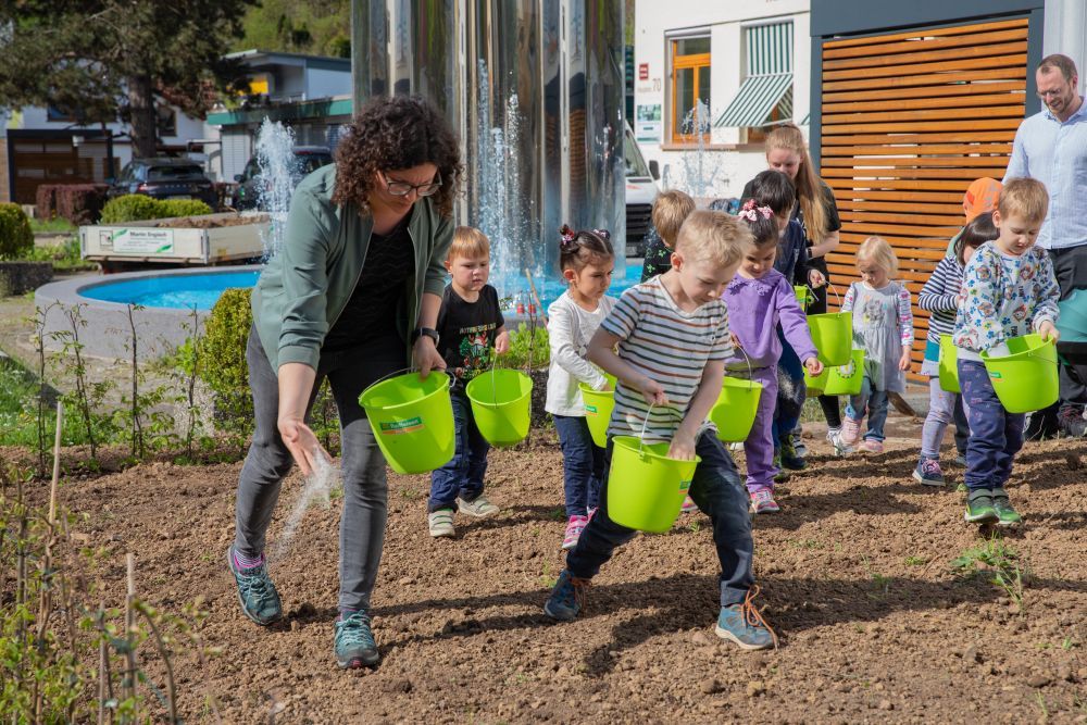 Kinder bringen Saatgut auf einer Fläche aus.