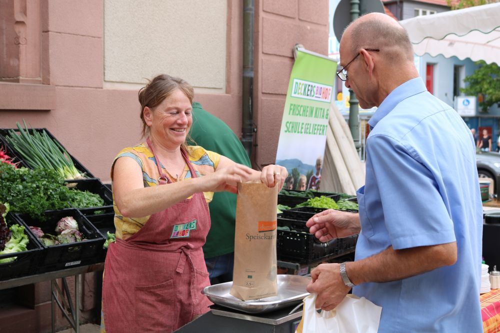 Eine Frau packt eine Papiertüte und gibt sie einem Mann.