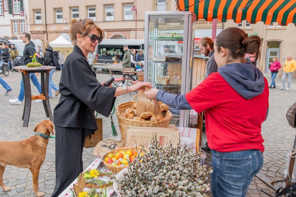 Eine Frau kauft an einem Markt-Stand ein.