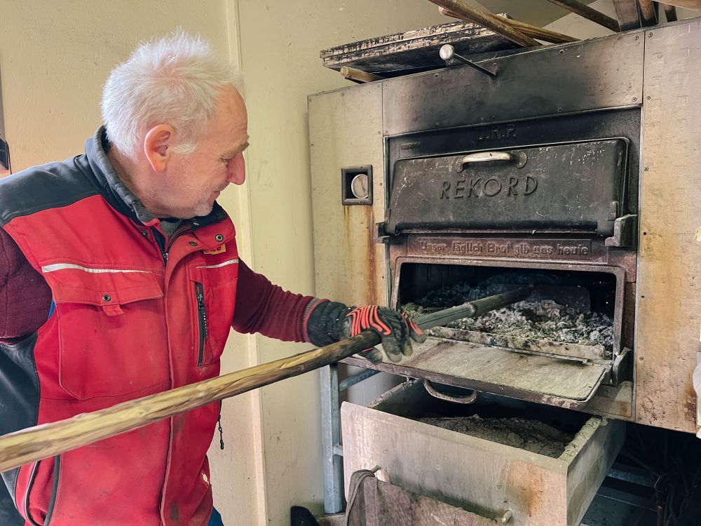 Horst Reiser holt die Holzkohle aus dem Ofen.
