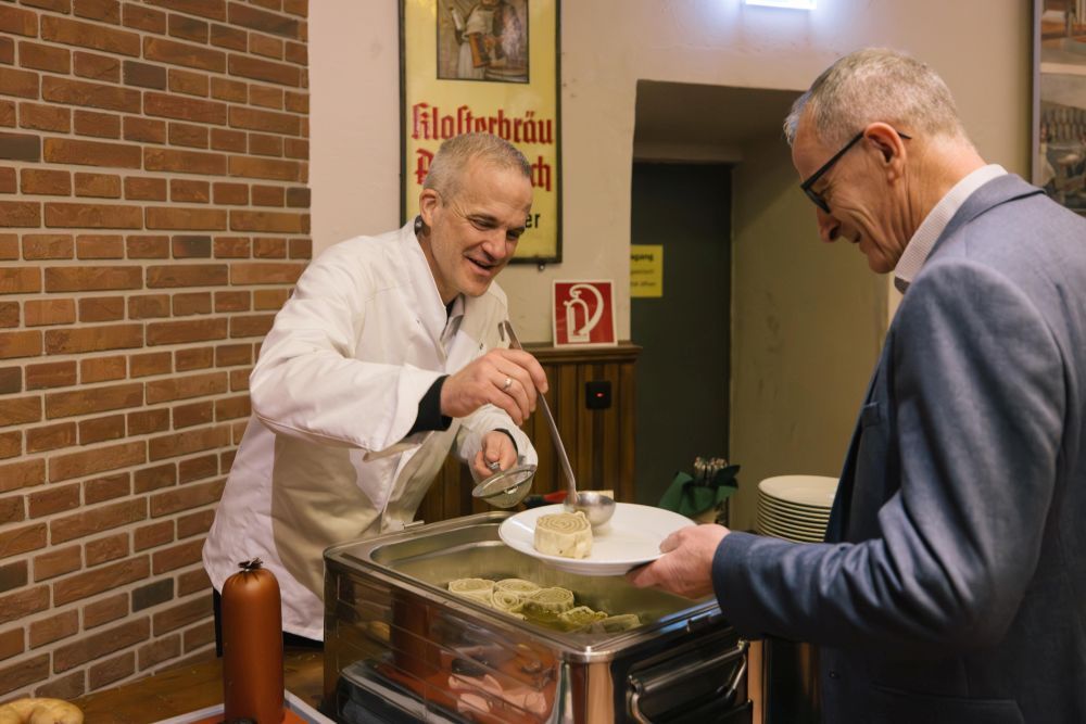 Metzger schöpft Maultaschen in einen Teller
