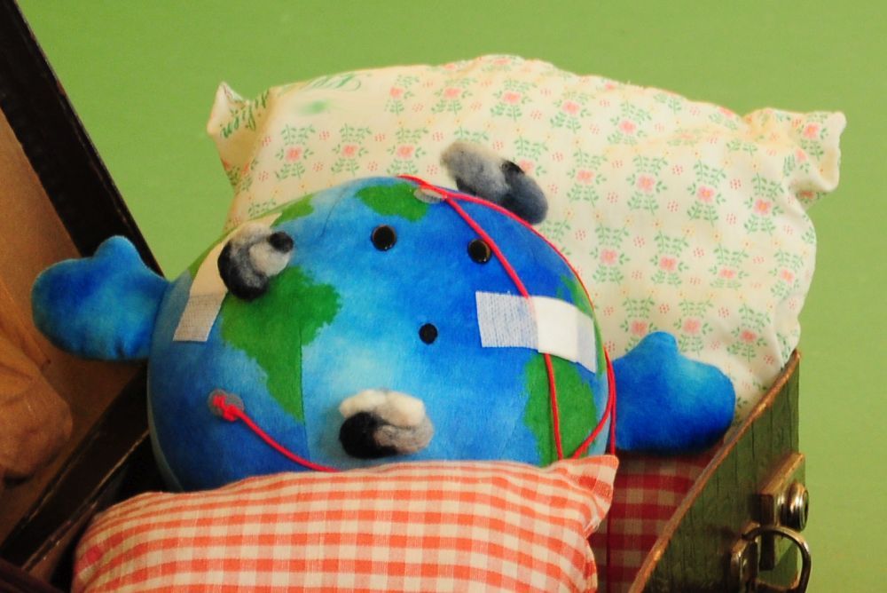 Die kleine, kranke Erde liegt in ihrem Koffer-Bett.