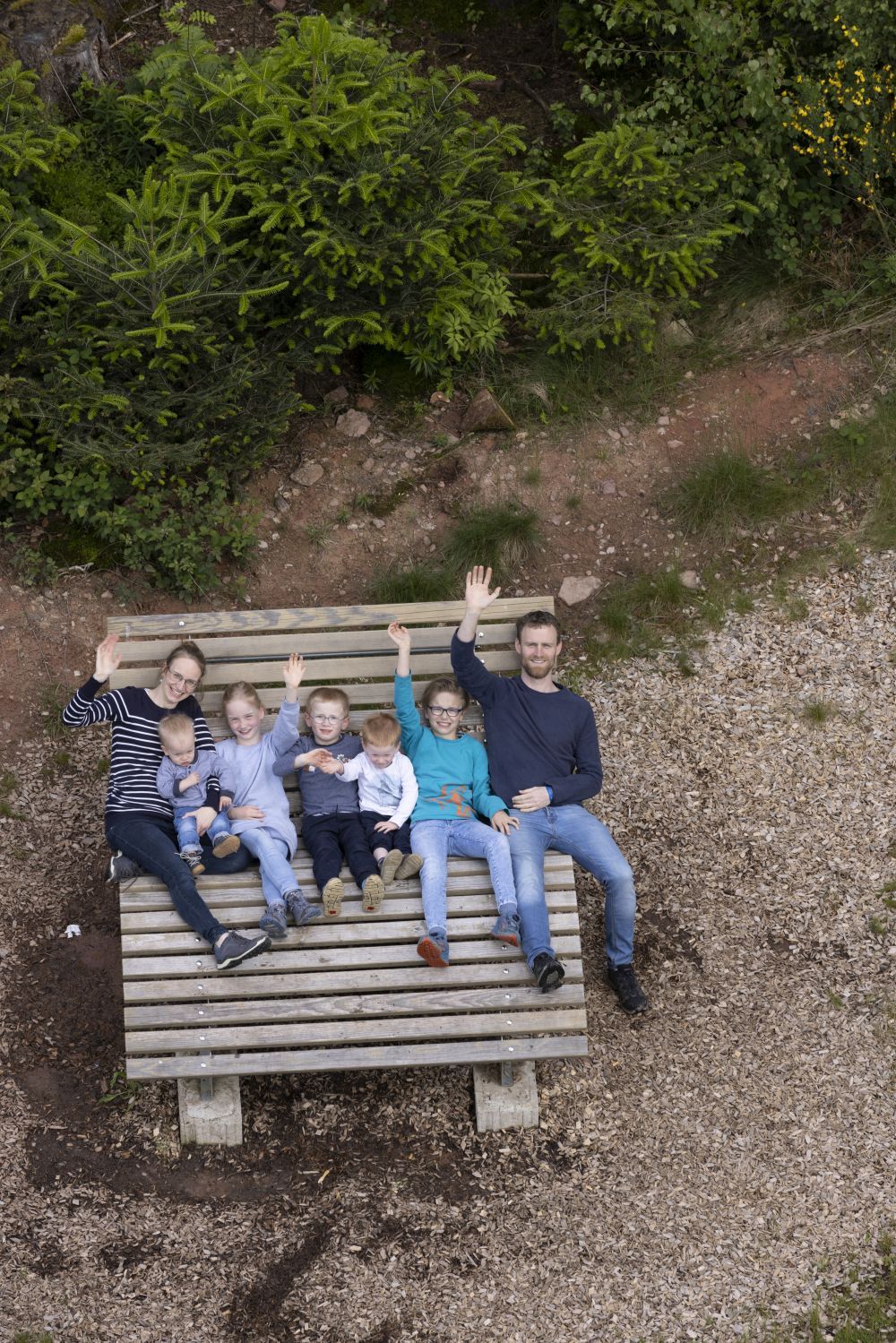 Familie liegt auf einer Sonnenliege und winkt