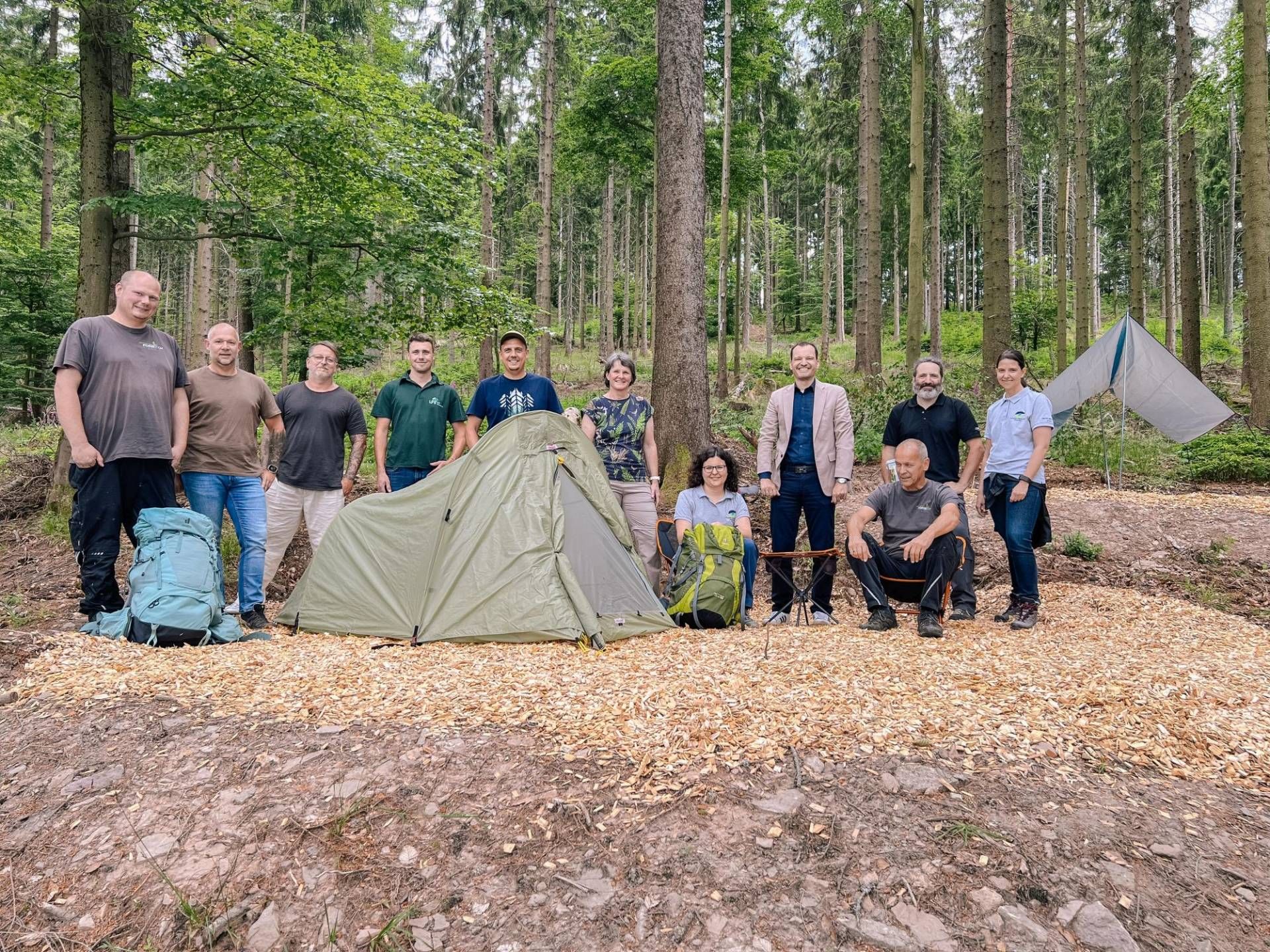 Menschen stehen mit zwei Zelten im Wald