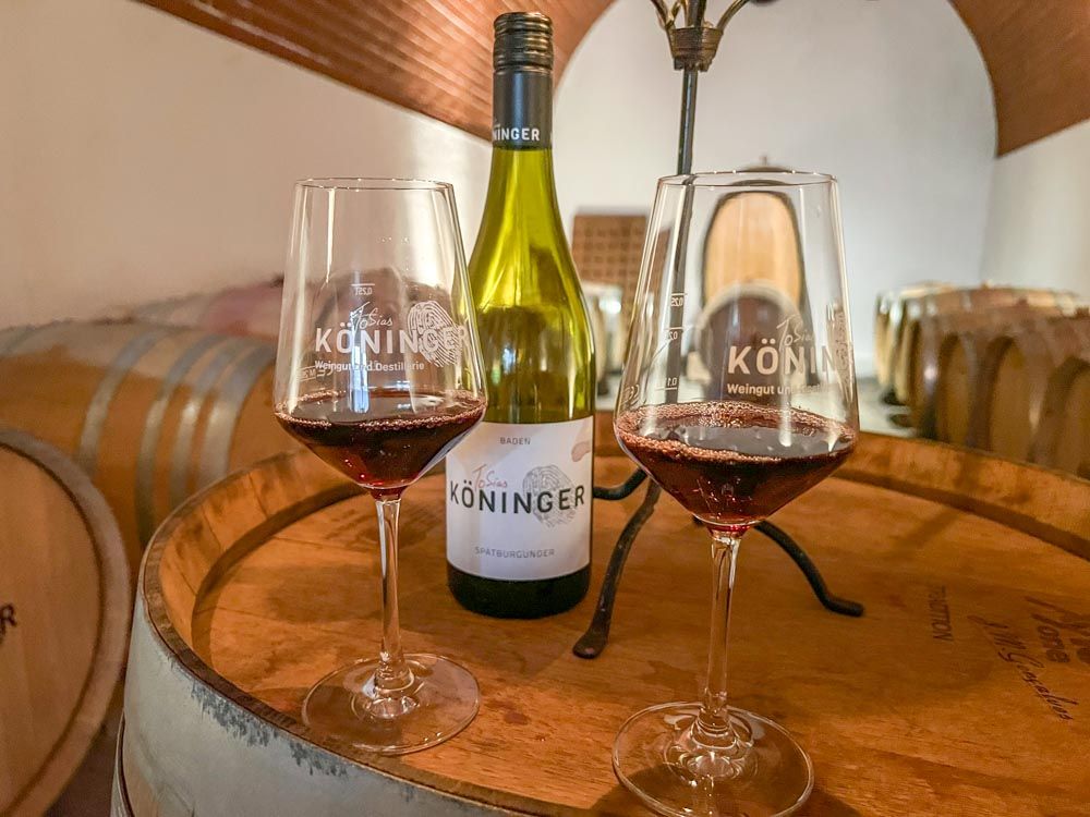Weinflasche auf Eichenfass mit zwei mit Rotwein gefüllten Gläsern