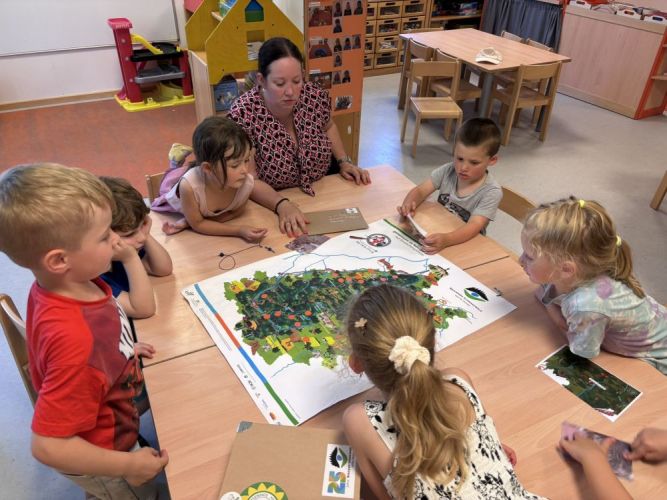 Erzieherin schaut mit Kindern die Naturpark-Karte an.