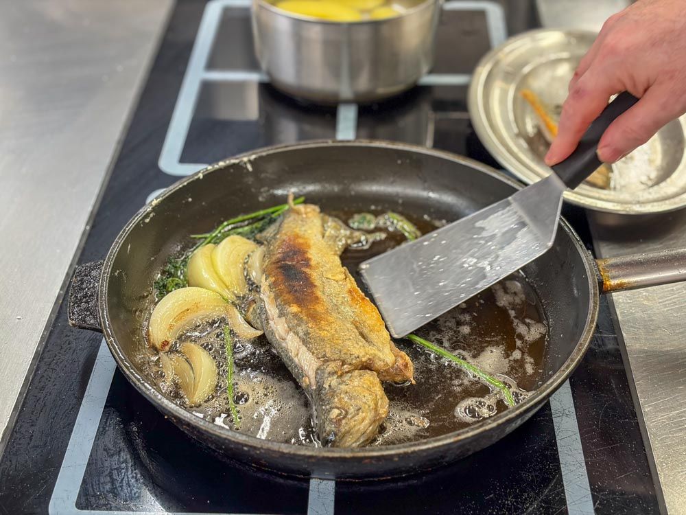 angebratene Schwarzwaldforelle in der Pfanne mit Butter, Zwiebeln und Petersilie