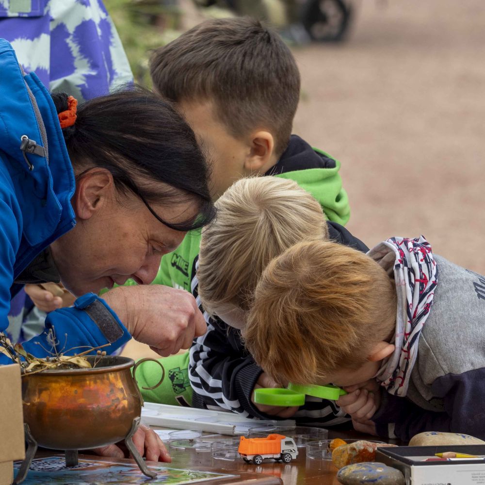 Zwei Kinder schauen sich durch eine Lupe etwas an.