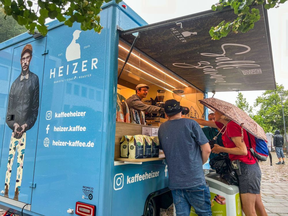 Menschen stehen vor einem Kaffee-Foodtruck.