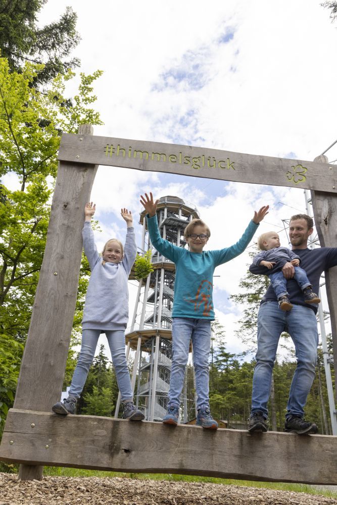 Vater steht mit Kindern in einem großen, hölzernen Bilderrahmen.