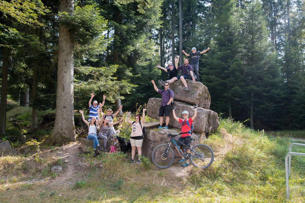 Menschengruppe um einen Felsen im Wald
