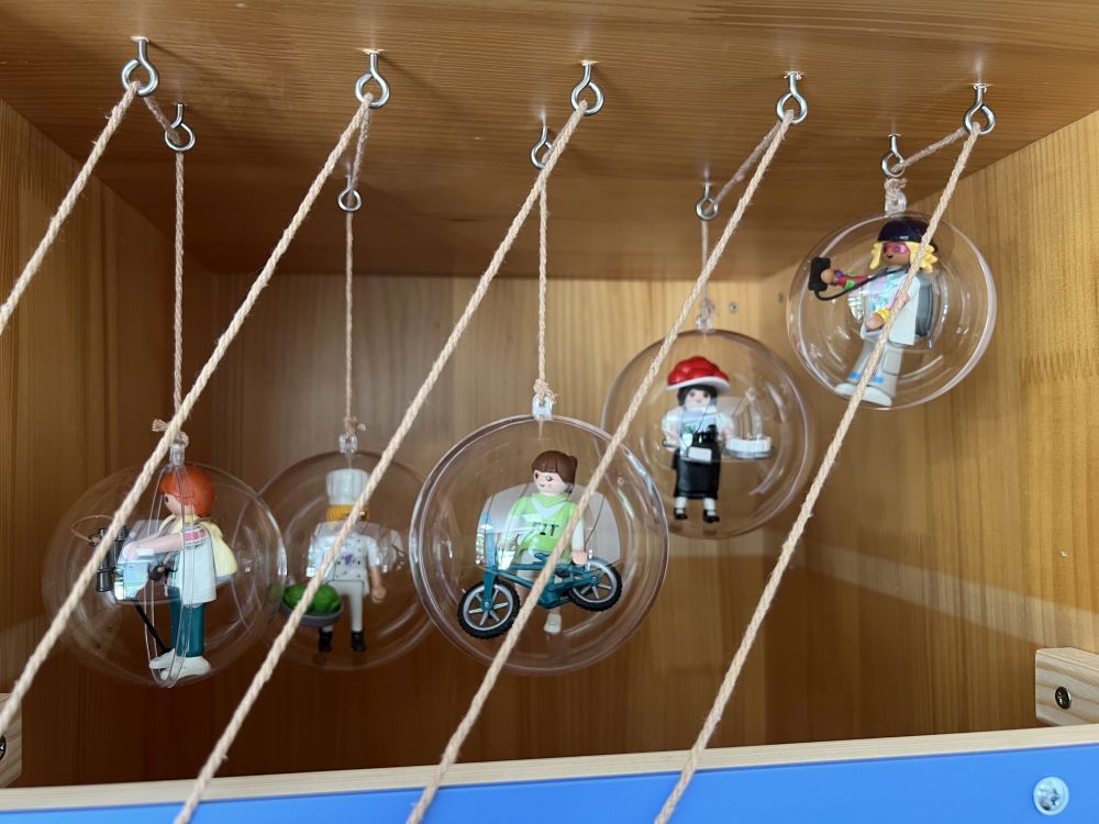 Playmobilfiguren in runden Kugeln an Fäden