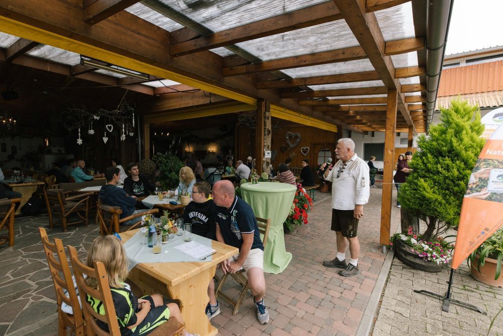Menschen sitzen an Tischen auf einem Hof