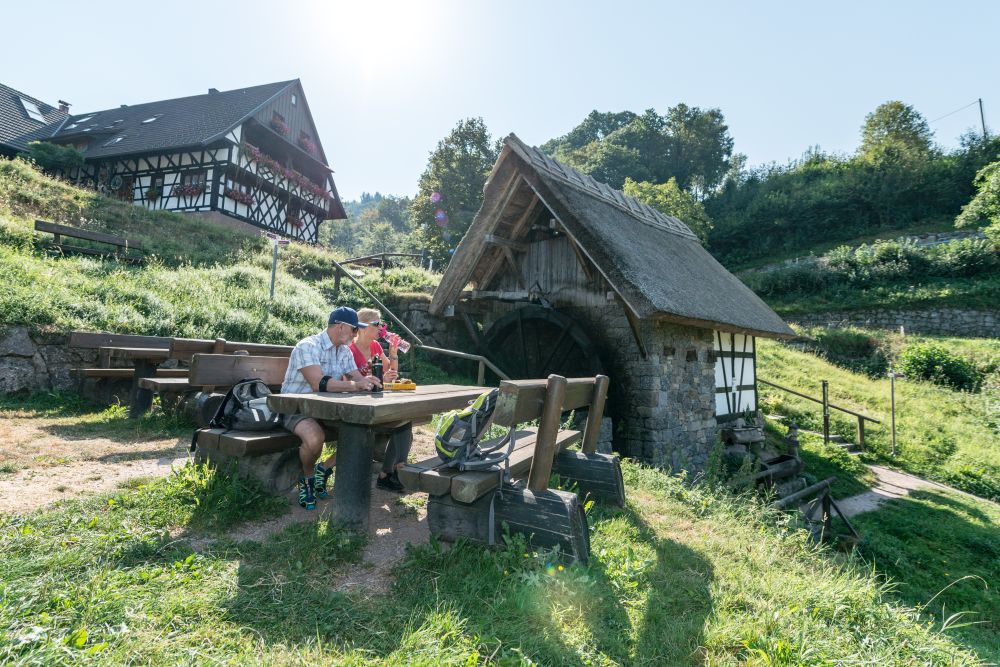 Paar macht Pause mit Vesper an einem Vespertisch und vor Fachwerkhäusern.