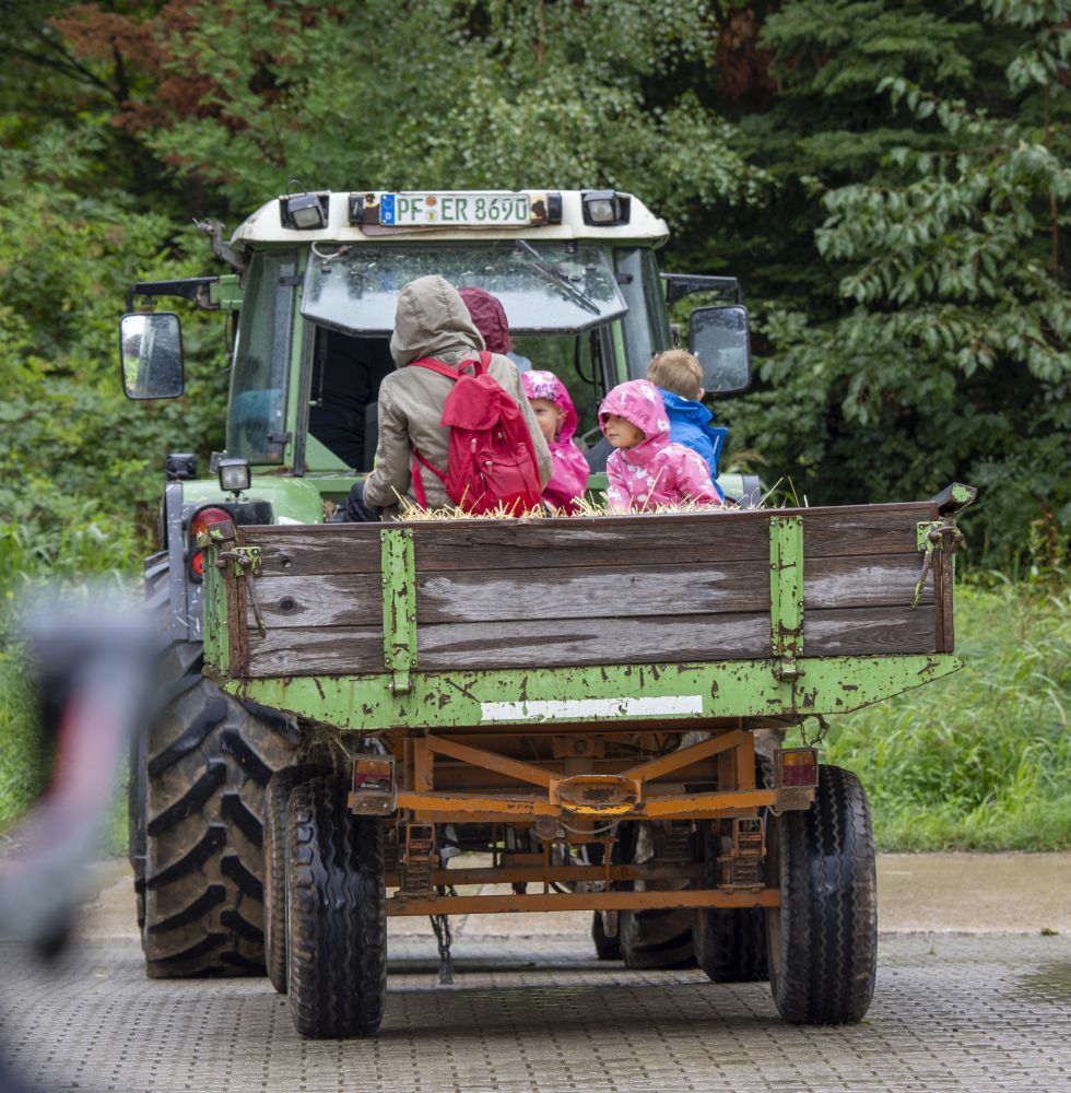 Menschen sitzen auf der Ladefläche eines Traktors.