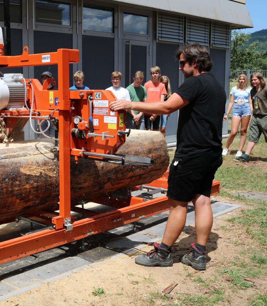 Lehrer mit Schülern an einem mobilen Sägewerk