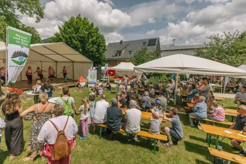 Gäste sitzen auf Bänken und schauen dem Auftritt einer Tanzgruppe zu.