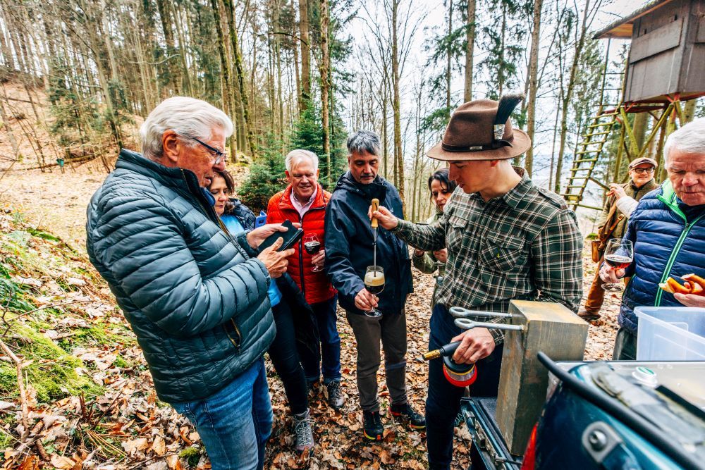Menschen stehen im Wald und verkosten Bier.