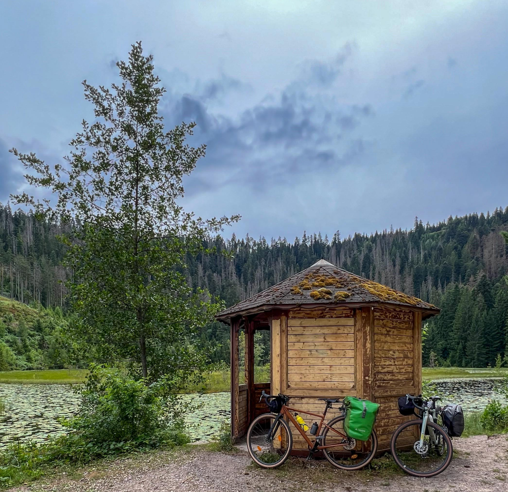 Gravel Bike lehnt an einem Holzpavillion an einem Karsee