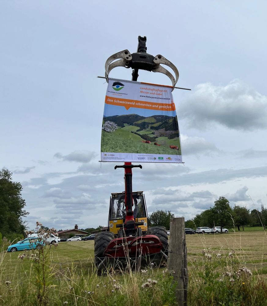 Ein Werbeplakat für den Brunch hängt an der Schaufel eines Traktors.