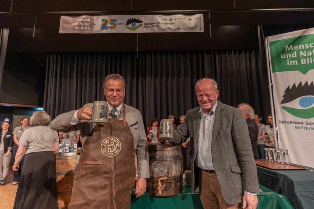 Minister Peter Hauk und Alpirsbacher-Geschäftsführer Carl Glauner prosten mit einem Bierhumpen in die Kamera.