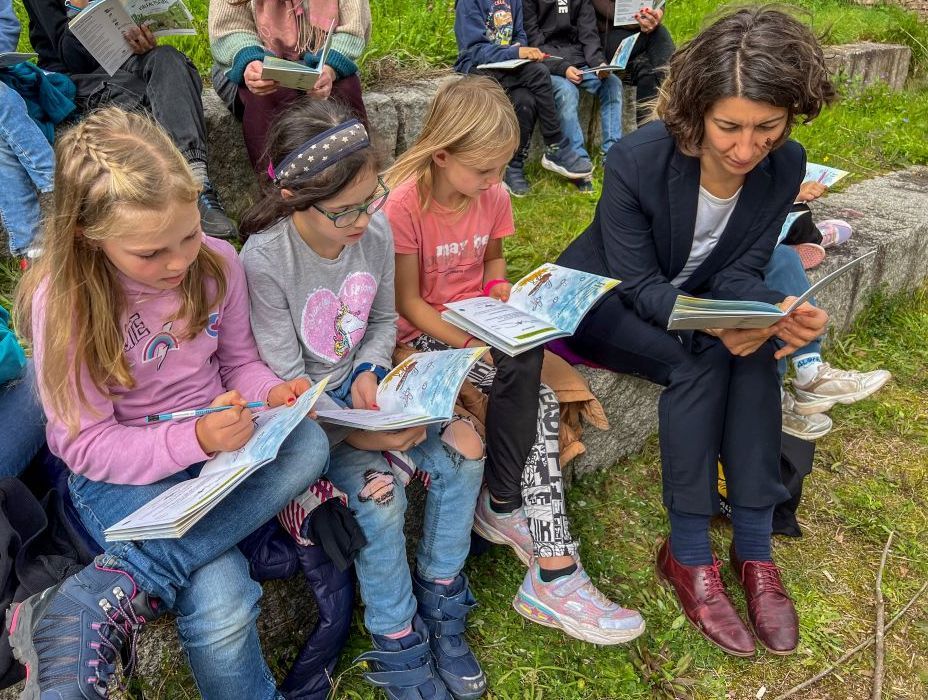 Kinder lesen in einem Heft und machen Aufgaben.