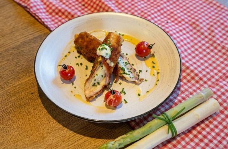 Spargel-Cordonbleu mit Tomaten und Sahnesoße auf einem Teller