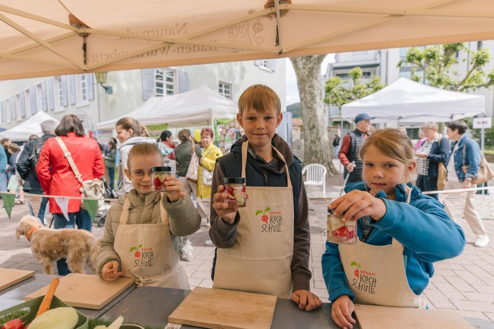 Drei Kinder zeigen ihr selbstgemachtes Eingemachtes in Gläsern.