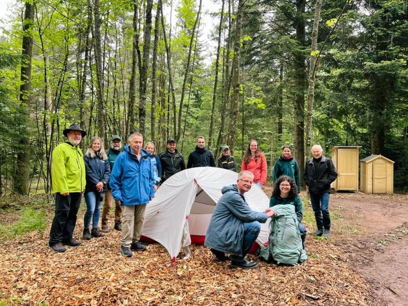 Ein Gemeinschaftsprojekt: das neue Trekking-Camp in Dobel.  Hier bei der Eröffnung:  vordere Reihe: Naturpark-Projektmanagerin Lilli Wahli mit Dobels Bürgermeister Christoph Schaack  hintere Reihe v. r.: der Naturschutzbeauftragte des Landkreises Calw Michael Conrad, die Stellv. Naturpark-Geschäftsführerin Yvonne Flesch, Dobels Tourismusleiterin Rahel Schilling, Katrin Dürr von Forst BW, René Skiba von Tourismus Nördlicher Schwarzwald, Patrick Schönthaler vom gleichnamigen Forstbetrieb, Heide Glasstetter von Schwarzwald Tourismus, Camp-Kümmerer Andreas Windhab, Andreas Werner und Kristine Weis von der Unteren Forstbehörde des Landratsamtes Calw und Camp-Kümmerer Peter Grambart.