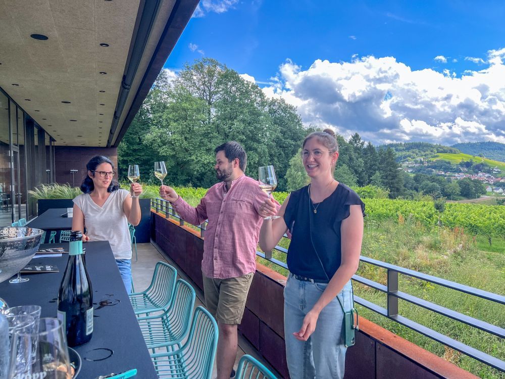 Drei Menschen prosten sich mit Weingläsern zu.